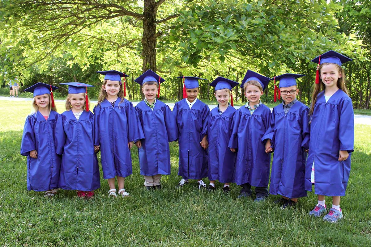 students standing outside in graduation gowns smiling