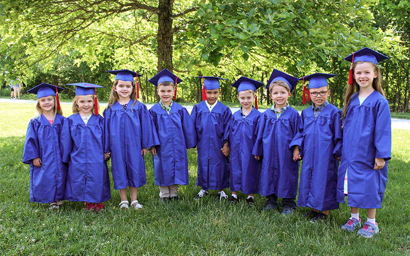 preschool graduation, children lined up outside, with blue hats and gowns on