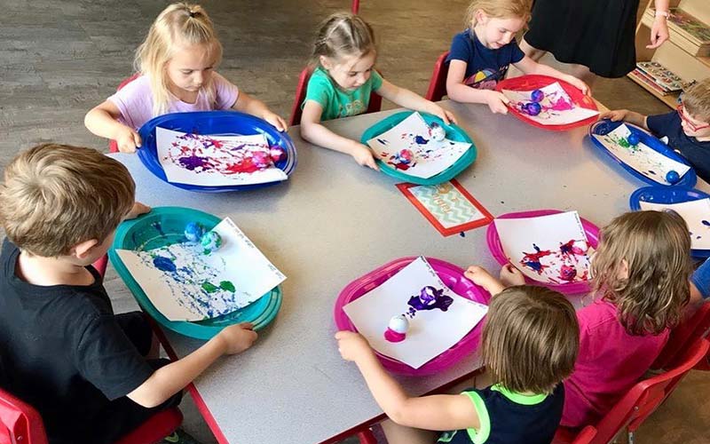 kids sitting at a table doing an art project