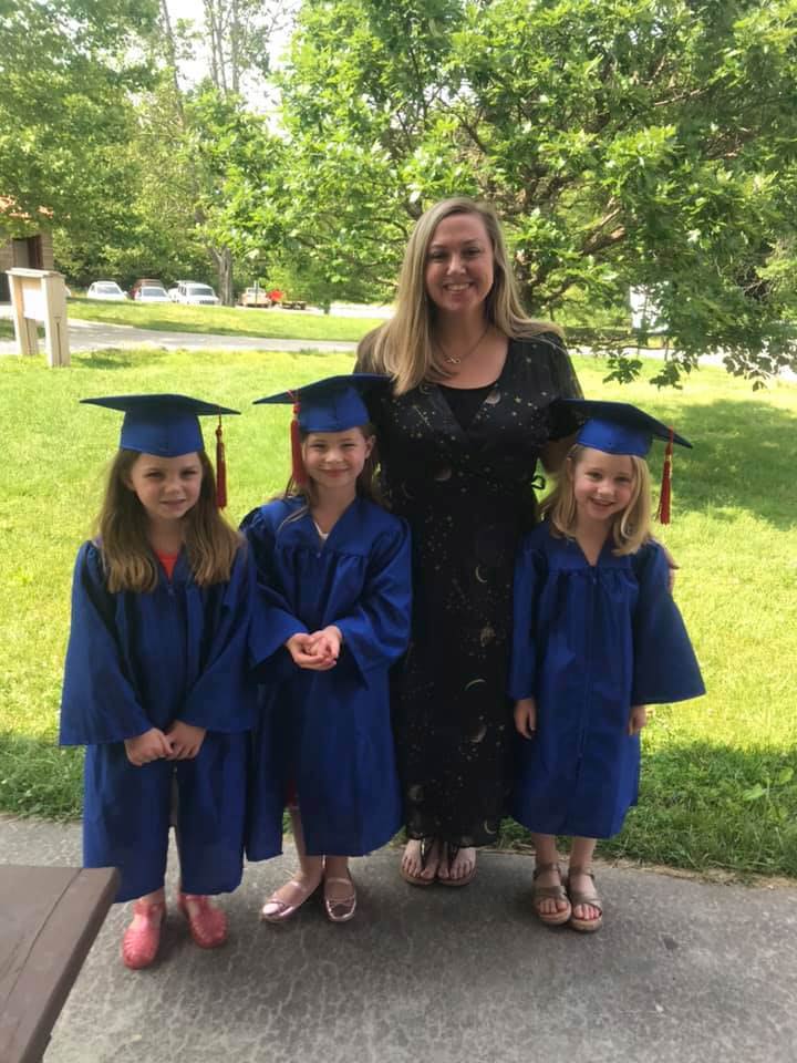 Michelle standing outside with three girls that have graduation gowns and caps on, smiling